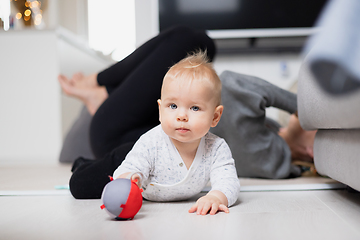 Image showing Happy family moments. Mother lying comfortably on children's mat watching and suppervising her baby boy playinghis in living room. Positive human emotions, feelings, joy