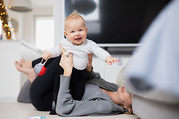 Image showing Happy family moments. Mother lying comfortably on children's mat playing with her baby boy watching and suppervising his first steps. Positive human emotions, feelings, joy.