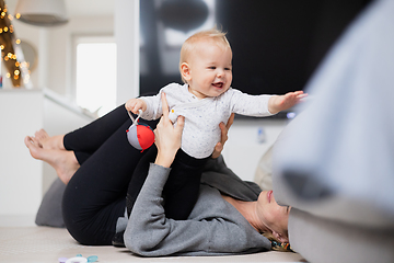 Image showing Happy family moments. Mother lying comfortably on children's mat playing with her baby boy watching and suppervising his first steps. Positive human emotions, feelings, joy.