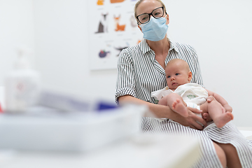 Image showing Mother holding her baby boy at medical appointment at pediatrician office.