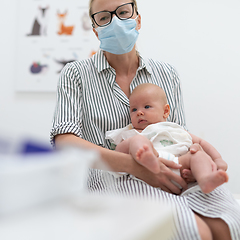 Image showing Mother holding her baby boy at medical appointment at pediatrician office.