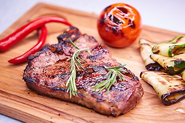 Image showing Grilled T-Bone Steak on serving board on wooden background