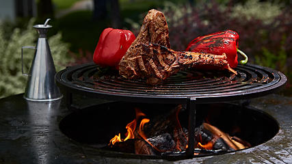 Image showing Tomahawk rib beef steak and T-bone on hot black grill.