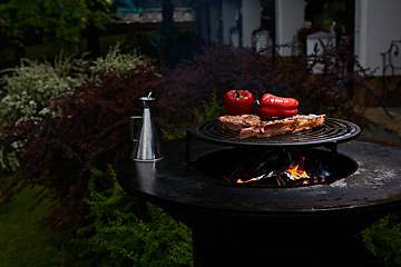 Image showing Tomahawk rib beef steak and T-bone on hot black grill.