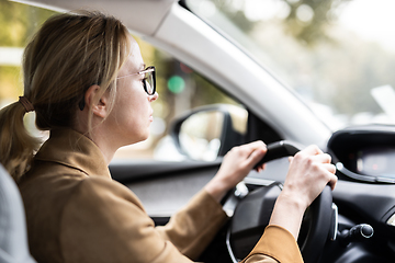 Image showing Business woman driving a car to work. Female driver steering car on the road