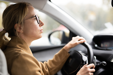 Image showing Business woman driving a car to work. Female driver steering car on the road