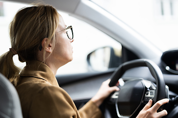 Image showing Business woman driving a car to work. Female driver steering car on the road