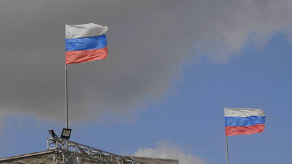 Image showing Russian flag on the flagpole waving in the wind against a blue sky with clouds