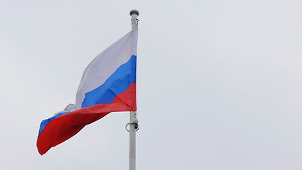 Image showing Russian flag on the flagpole waving in the wind against a blue sky with clouds