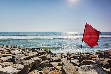 Image showing Red flag on rocky beach