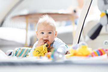 Image showing Cute baby boy playing with hanging toys arch on mat at home Baby activity and play center for early infant development. Baby playing at home