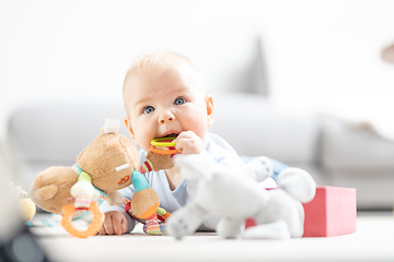 Image showing Cute baby boy playing with toys on mat at home Baby activity and play center for early infant development. Baby playing at home.