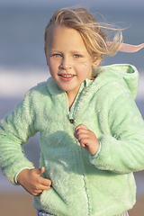 Image showing A 5-year-old girl in a green jacket is running