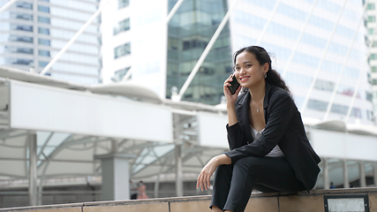 Image showing Happy smiling businesswoman sitting talk on mobile phone outside street city near office