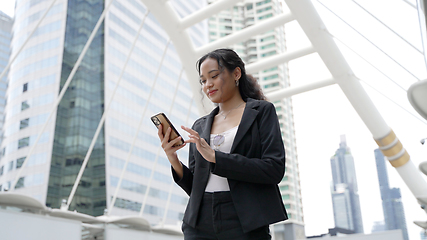 Image showing Asian executive working woman holding and using mobile phone in the street