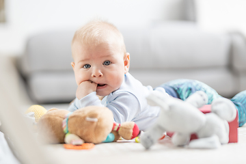 Image showing Cute baby boy playing with hanging toys arch on mat at home Baby activity and play center for early infant development. Baby playing at home