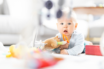 Image showing Cute baby boy playing with hanging toys arch on mat at home Baby activity and play center for early infant development. Baby playing at home