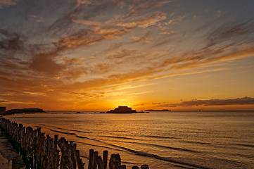 Image showing Golden sea sunset on the background of vintage wooden breakwaters