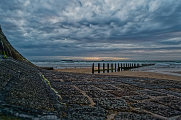 Image showing Dramatic seascape with feather clouds. Rocky coastline with wooden breakwaters