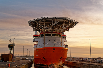 Image showing A huge merchant sea vessel in the port lock against the sky at sunset