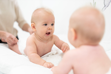 Image showing Beautiful shot of a cute baby boy looking at his reflection in big mirror.