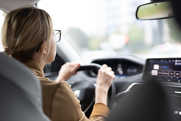 Image showing Business woman driving a car to work. Female driver steering car on the road