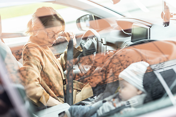 Image showing Mother fastening seat belt, driving family car, running errands while her baby sleeps in infant car seat by her site.