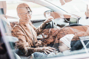 Image showing Mother concentrating on driving family car running errands while her baby sleeps in infant car seat by her site.