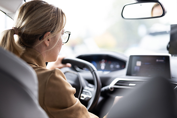 Image showing Business woman driving a car to work. Female driver steering car on the road