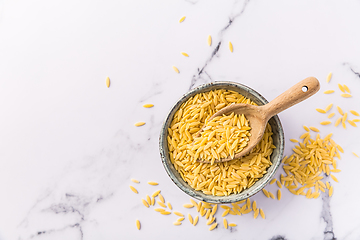 Image showing Raw orzo pasta (risoni) in bowl with wooden spoon