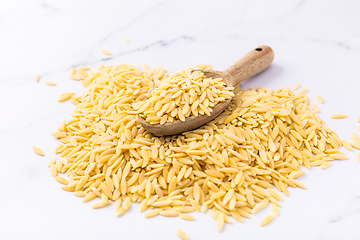 Image showing Raw orzo pasta (risoni) with wooden spoon