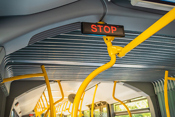 Image showing Stop sign in city bus. Empty bus interior. Bus with blue seats and yellow handrails