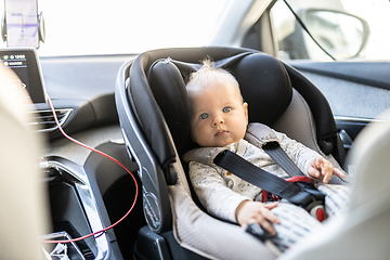 Image showing Cute little baby boy strapped into infant car seat in passenger compartment during car drive.