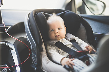 Image showing Cute little baby boy strapped into infant car seat in passenger compartment during car drive.