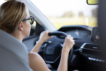 Image showing Business woman driving a car to work. Female driver steering car on the road