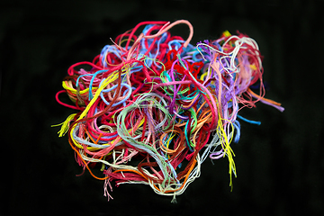 Image showing Ball of multicolored tangled threads for needlework on black bac