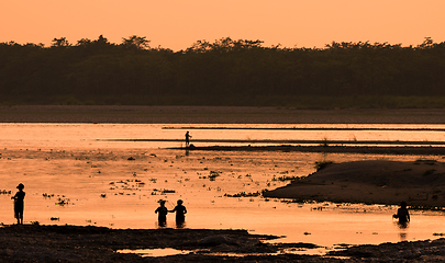 Image showing Asian women fishing in the river, silhouette at sunset