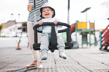 Image showing Mother pushing her infant baby boy child on a swing on playground outdoors.