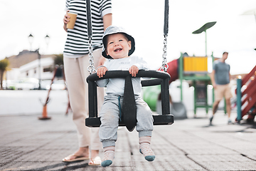 Image showing Mother pushing her infant baby boy child on a swing on playground outdoors.