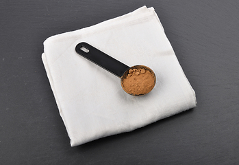 Image showing Carob powder in measuring spoon on shale