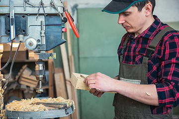 Image showing Carpenters with electric drill machine drilling wooden board