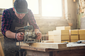 Image showing Worker grinds the wood box