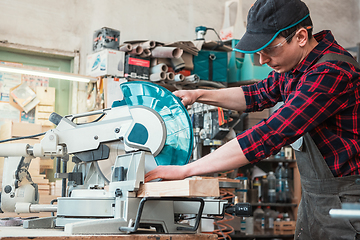 Image showing Carpenter worker cutting wooden board