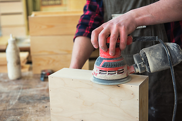 Image showing Worker grinds the wood box