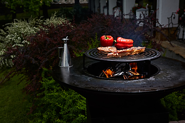 Image showing Tomahawk rib beef steak and T-bone on hot black grill.