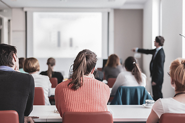 Image showing Speaker giving presentation in lecture hall at university. Participants listening to lecture and making notes