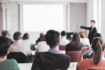 Image showing Speaker giving presentation in lecture hall at university. Participants listening to lecture and making notes