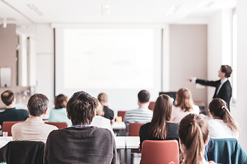 Image showing Speaker giving presentation in lecture hall at university. Participants listening to lecture and making notes