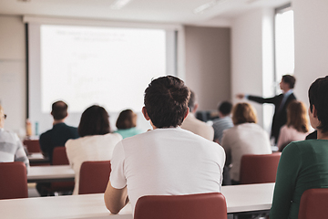 Image showing Speaker giving presentation in lecture hall at university. Participants listening to lecture and making notes