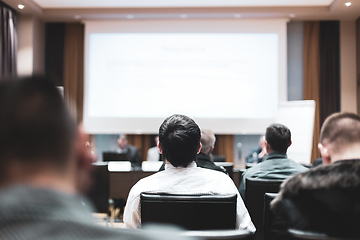 Image showing Business and entrepreneurship symposium. Speaker giving a talk at business meeting. Audience in the conference hall. Rear view of unrecognized participant in audience